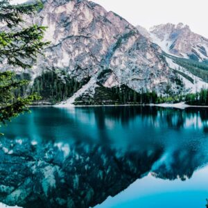 Serene mountain lake with stunning reflections in Braies, Italy, surrounded by trees.